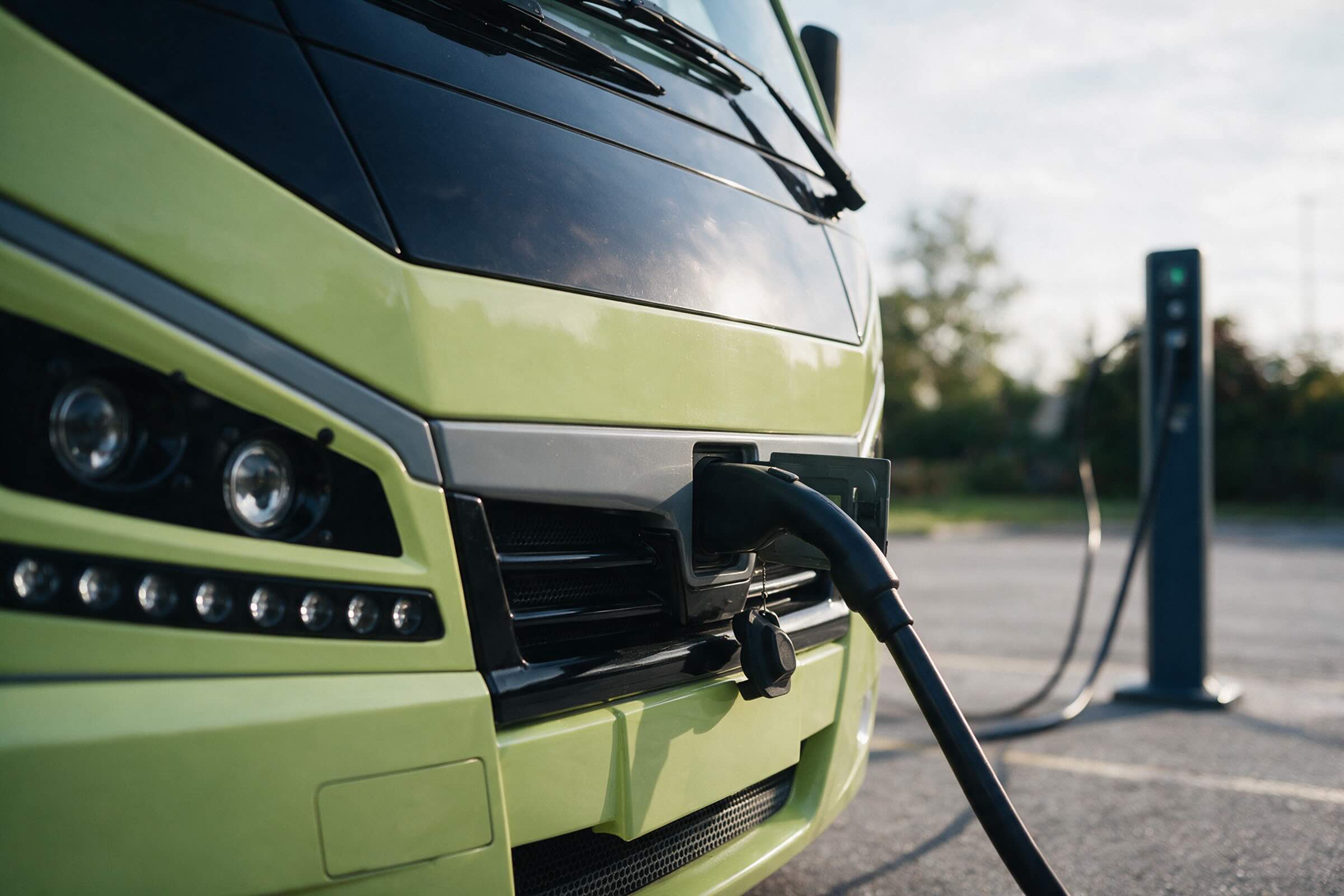 An Argo bus plugged into a charger, the cable connected at the front of the vehicle